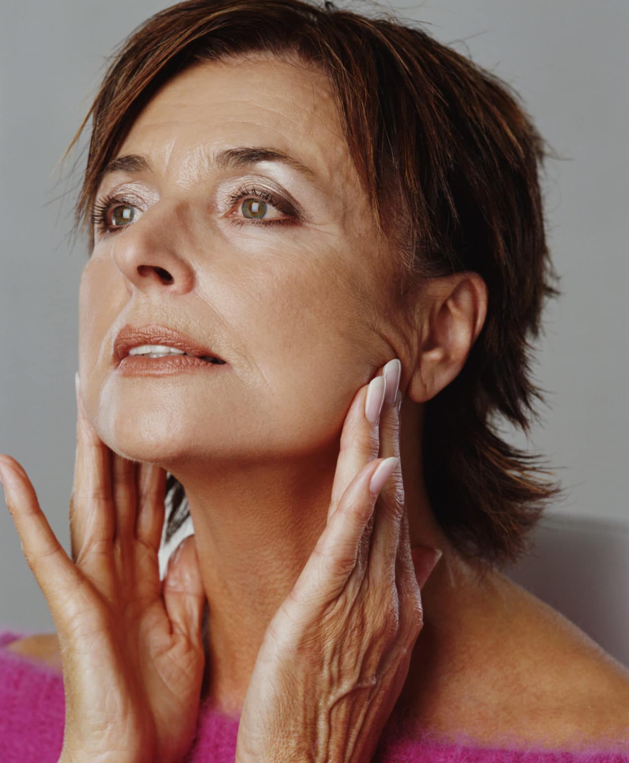A person with wrinkles pulling on the skin around their chin to smooth it.