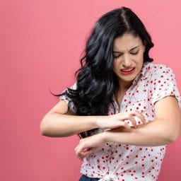 Young woman scratching her itchy arm.