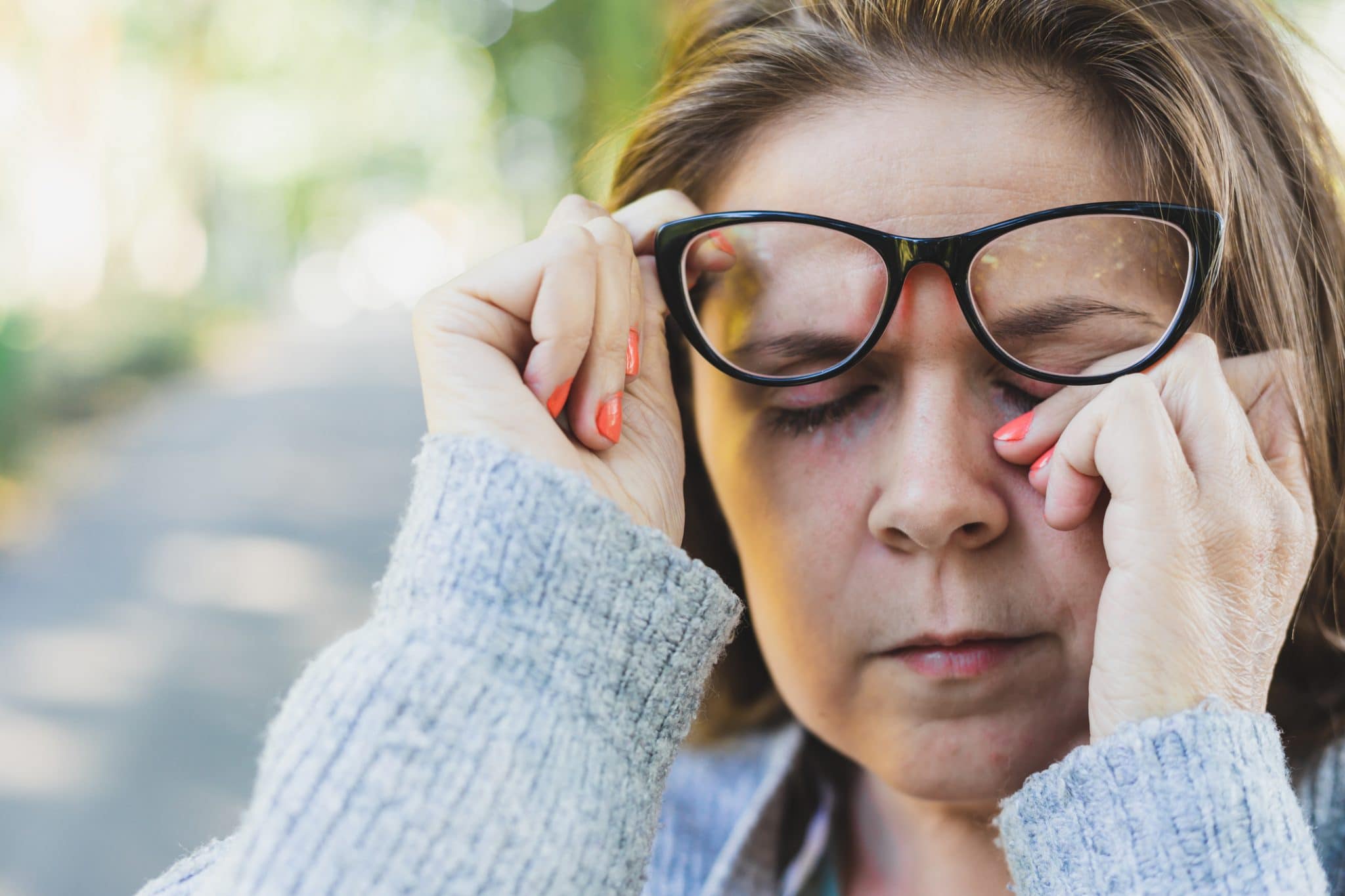 Close up shot of young woman rubbing her eye while outdoors