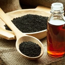Black cumin on wooden spoon and essential oil.