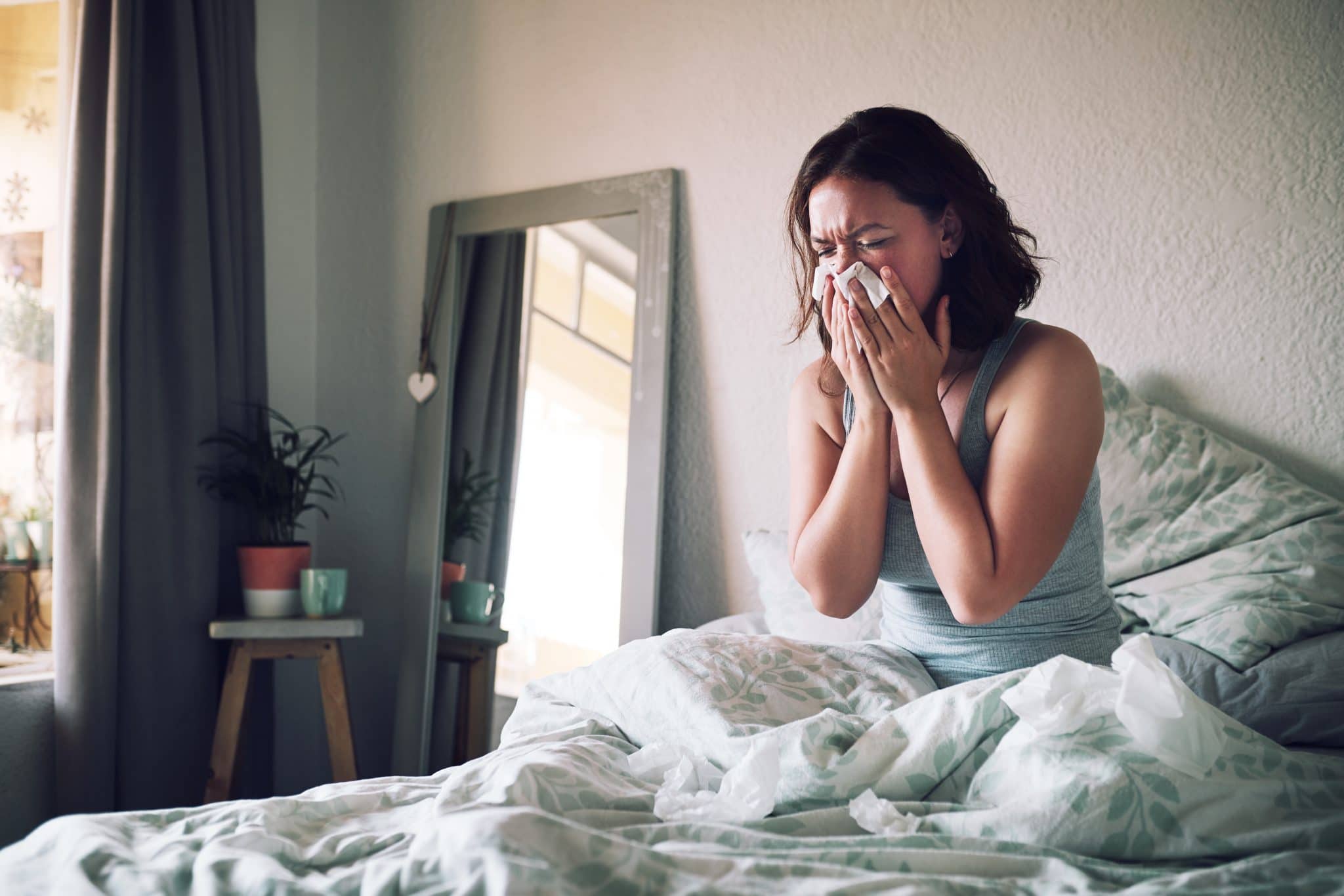 Woman blowing her nose while in bed.