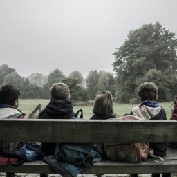 A group of children gathering on a bench outside.