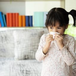 Little girl with allergies blowing her nose.