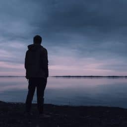 A silhouette of a lone man standing on a beach.