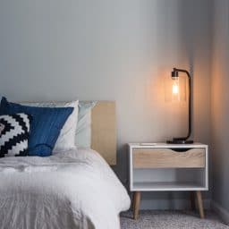 Photo of a bed next to a night stand indoors.