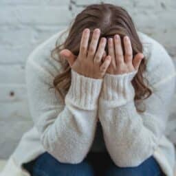 Woman with hands over her face experiencing extreme fatigue.