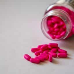 Pink capsules in a clear pill bottle.