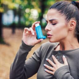 Young woman treating her asthma with an inhaler.