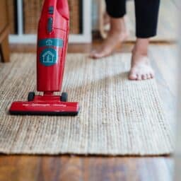 A person vacuuming a rug at home.