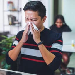 Shot of a young man blowing his nose