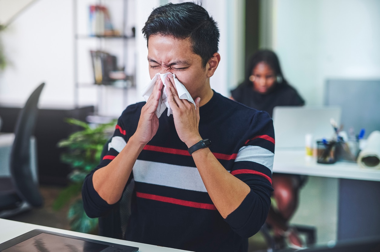 Shot of a young man blowing his nose.