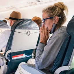 Woman sneezing into a tissue on a plane