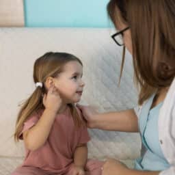 Young girl pointing at her ear to show her mom that it hurts