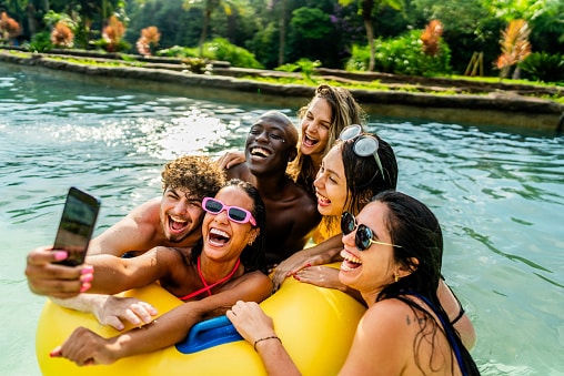 Friends hanging out in a pool, taking a picture.