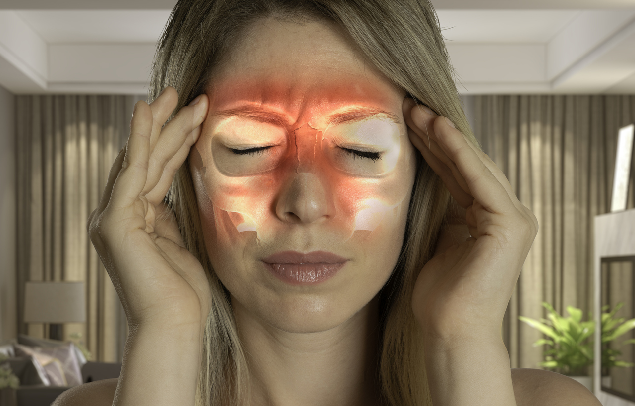 Woman holding her head. Red color illustrates inflamed sinuses.