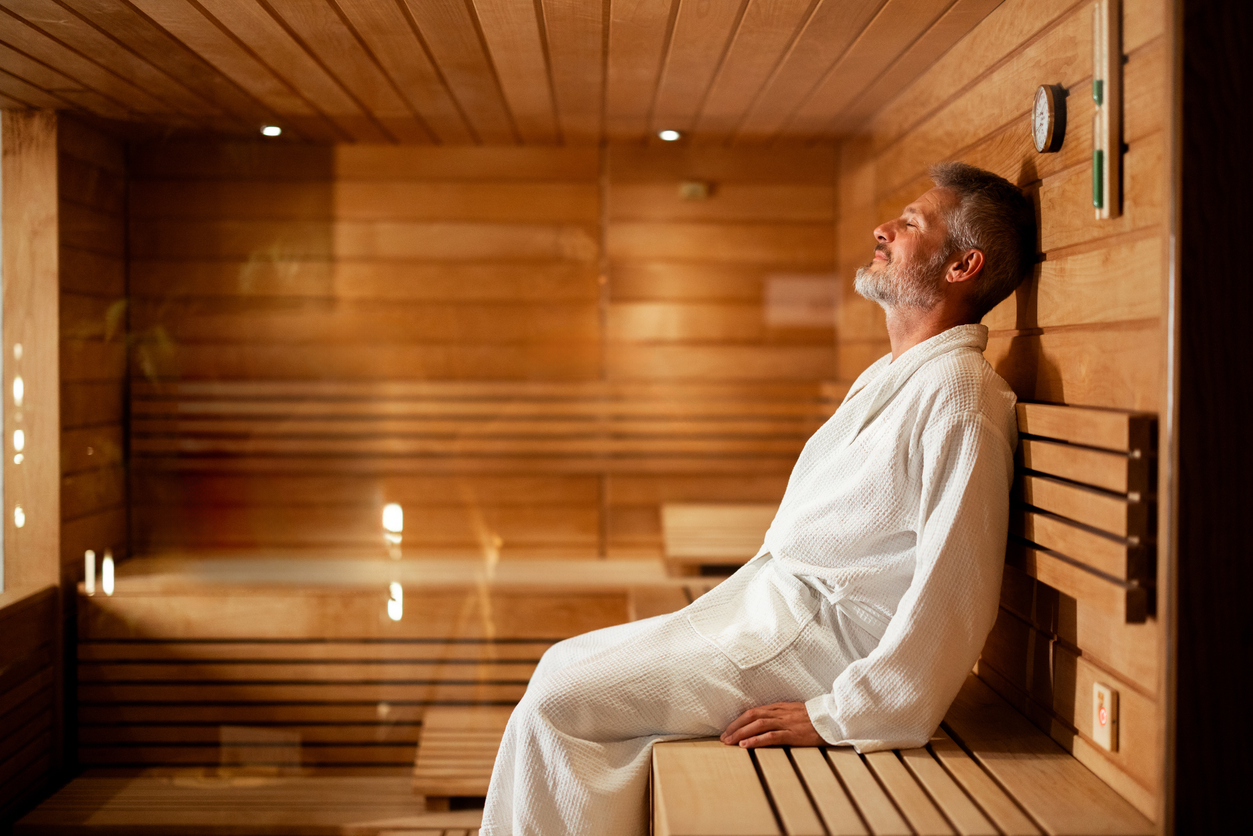 Man in white robe relaxing inside a wooden sauna, embracing warmth and well-being