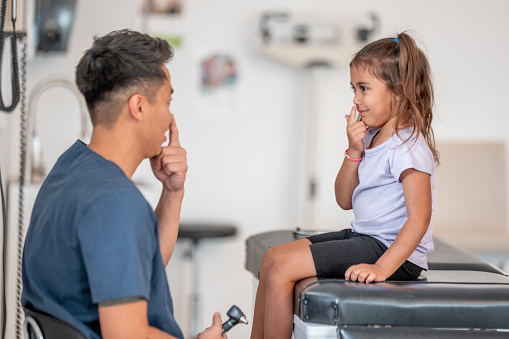 Pediatric ENT specialist touches his nose and a young patient mirrors him. She's there for a nose exam.
